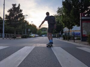 A skateboarder cruising into the street view from the back